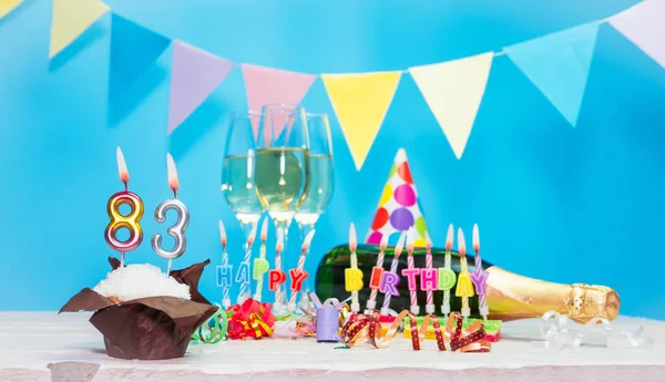 Doğum tarihi, mumlar ve 83 numara. Yıldönümü tebrik kartı. Tatil süslemeleri. Mutlu doğum günü mumları. Çok renkli çelenklerle süslenmiş.