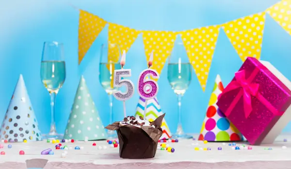 Doğum günü kutulu bir kadın ya da kız için doğum tarihi. 56 mumlu turta. Yıldönümü kartı ve şampanya. Tatil süslemeleri. Mutlu yıllar.