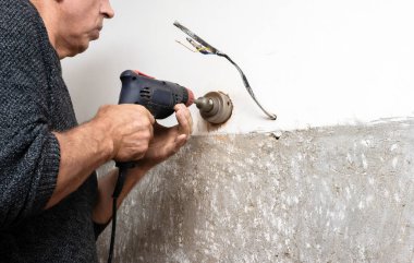 Bir elektrikçi duvarı deliyor, bir soket kutusunu duvara yerleştiriyor, bir elektrikçi prizleri takıyor, profesyonel bir tamirci