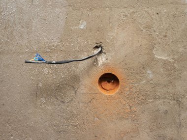 Tuğla bir duvara soket, soket matkabı, elektrik tamiratı yapan bir işçi, duvardaki elektrik kabloları.