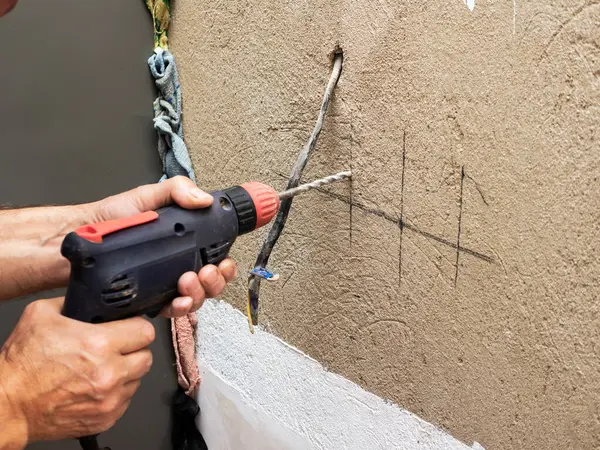 Drilling a hole in the wall for an outlet, installing an electrical outlet in the wall