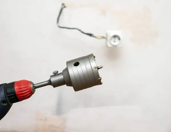 Installation of sockets in the house. A hammer drill with a drill for drilling electrical sockets. Construction tools for drilling in a brick wall.