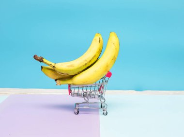 Arka planda süpermarket arabasında muz. Market sepetinde yasaklı yaratıcı bir resim..