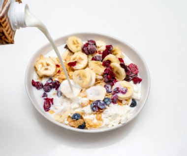 Böğürtlenli muz, süzme peynir ve mutfakta bir tabakta kuru üzüm. Müsli 'ye süt dök süzme peynirli, kirazlı ve böğürtlenli.