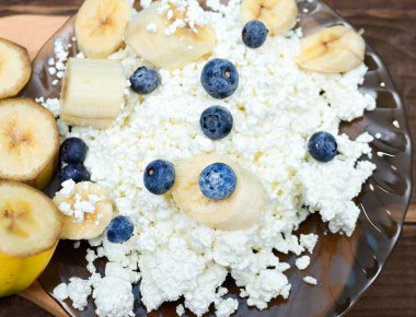 Peynirli süzme peynir ve muz karışımı bir tabakta, kahvaltıda yabanmersini ve peynir, spor beslenmesinde böğürtlen ve süzme peynir