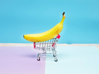 Arka planda süpermarket arabasında muz. Market sepetinde yasaklı yaratıcı bir resim..