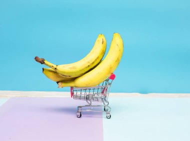 Arka planda süpermarket arabasında muz. Market sepetinde yasaklı yaratıcı bir resim..