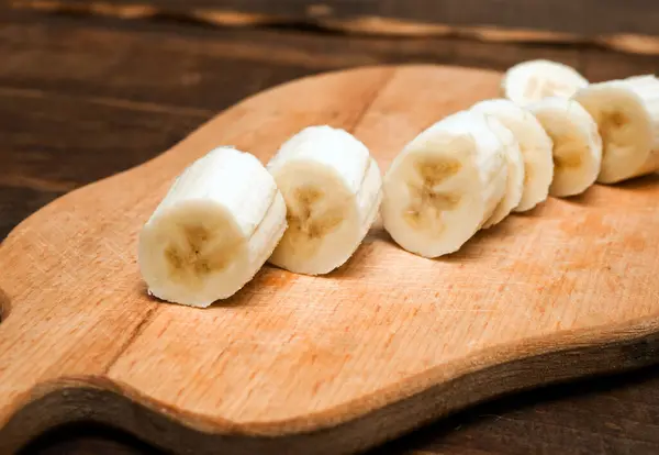Appetizing sliced banana on a kitchen cutting board close-up. Banana slices without peel.