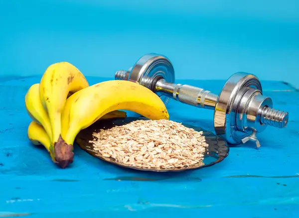 Healthy sports nutrition, Bananas with oatmeal with fresh milk in a glass. On a blue board, ripe bananas on a blue wooden table.