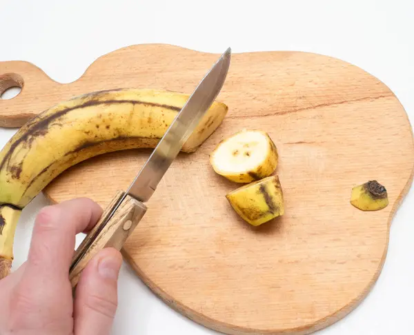 Cut bananas into slices on a wooden kitchen board, banana pieces without peel.