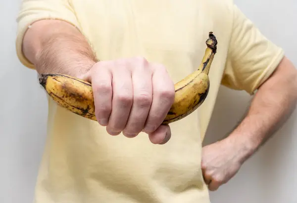 A banana is in the hands of a man in a peel. Holding bananas in a man\'s strong hand