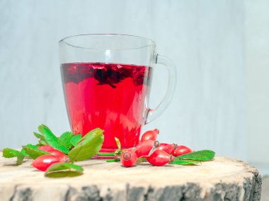 Terapötik gül çayı, şeffaf bir fincanda kırmızı çay, kırmızı gül tentürü. Homeopati, naturopatik çay. meyve suyu