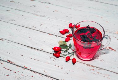 Terapötik gül çayı, şeffaf bir fincanda kırmızı çay, sağlık için bitkisel tortulu gül üzümü. Homeopati, naturopatik çay. meyve suyu