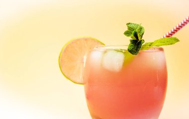 Bardakta pipetle limonata. Nane aromalı, turuncu buzlu yaz içeceği. Şeffaf bardakta soda. Sarı arka plan fotokopi alanındaki Apperol alkollü içecek..