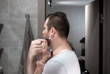 Bıçakla tıraş olur, sakalını tıraş eder..