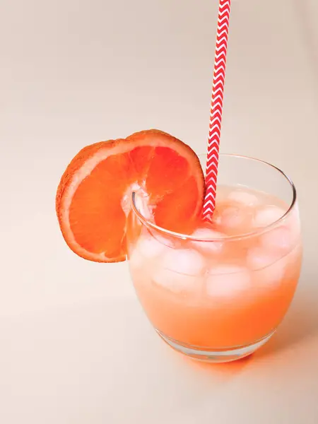 Lemonade with a straw in a glass. Summer orange drink with orange slice. Soda in a transparent glass. Apperol alcoholic drink. Natural juice with ice.