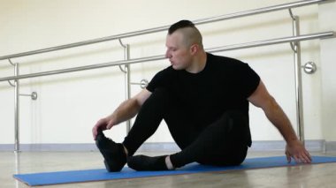 Erkek balerin koridorda ısınıyor. Bir balerin, bale barının yanında ayaklarını uzatır. Genç ve yakışıklı dansçı provada..