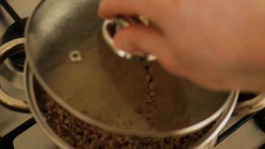 Manzara güzel, adam mutfakta tavada yemek hazırlıyor. Tencerede karabuğday lapası. Karabuğday lapası pişir. Buharlı karabuğday lapası.