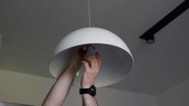 Adamın biri yanmış bir ampulü vidalıyor. Işıklıyı lambayla değiştirmek. İçerideki tavan arası ışığı. Enerji tasarrufu kavramı.