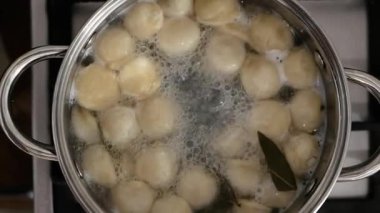 Manzara, hamur köfteleri tavada kaynatılır. Tavada kaynamış hamur köftesi. Mutfakta ağır çekimde yemek pişirmek.