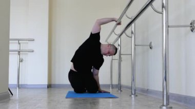 Balerin salonda ısınıyor. Bir balerin, vücudunu bale barının yanında ısıtıyor. Genç ve yakışıklı dansçı provada.