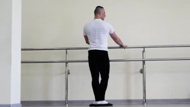 Profesyonel klasik bale eğitimi sırasında ısınıyor. Bir balerin, bir bale barında ısınıyor. Bale ayakkabılı genç adam salonda prova yapıyor.