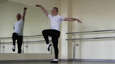 Profesyonel klasik bale eğitimi sırasında ısınıyor. Bir balerin, bir bale barında ısınıyor. Bale ayakkabılı genç adam salonda prova yapıyor..