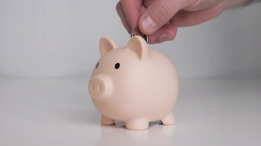 Para biriktiriyorum, domuz kumbarasında. Bir adam parayı kavanoza atarak biriktirir. Bankada madeni paralar
