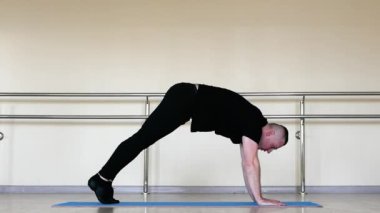 Paspasın üzerinde yoga, antrenmanda esneme hareketleri. Bale eğitimi, genç bir adam plastik koreografi yapıyor. Klasik dans sıcaklığı.