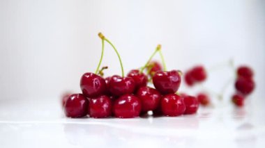  Olgun kiraz, beyaz bir masaya yavaş çekimde güzel bir şekilde düşer. Sonbaharda beyaz arka planda kiraz üzümü