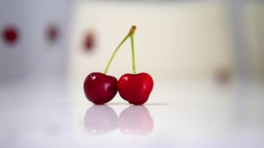 Olgun kiraz, beyaz bir masaya yavaş çekimde güzel bir şekilde düşer. Sonbaharda beyaz arka planda kiraz üzümü.