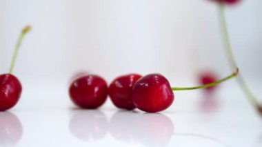 Yumuşak odaklı kamera, olgun kiraz çileği beyaz bir masaya yavaş çekimde güzel bir şekilde düşer. Sonbaharda beyaz arka planda kiraz üzümü.