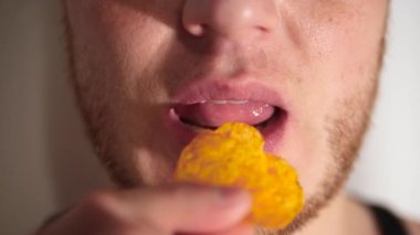 Bir adam cips yer, ağzını kapatır, ağzına patates cipsi koyar, ağır çekimde.