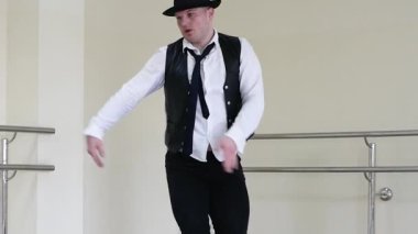 Yaratıcı caz kıyafetleri içinde yakışıklı genç bir dansçı. Kravatlı ve siyah yelekli modern bir dansçı. Koridorda duvarın arkasında antrenman yapıyor.