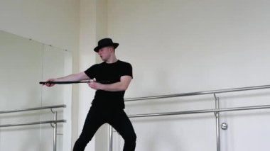 Kabare ya da stüdyoda bastonlu caz dansı. Siyah gangster şapkalı ve siyah elbiseli genç bir adam ellerinde sopayla blues yapıyor..