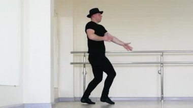 Siyah şapkalı çılgın ve enerjik bir dansçı. Kolları ve vücudu hızlı hareket eden genç bir adamın yaratıcı ve enerjik dansı. Caz ayakkabılı adamlar stüdyoda dans ediyor..