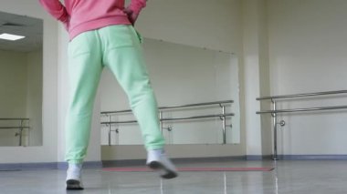  Zıplayan beyaz spor ayakkabılı bir dansçının bacakları modern bir balerin dans salonunda ısınıyor..