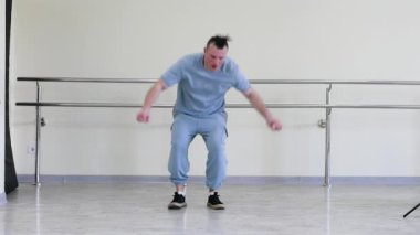Stüdyodaki hilelerle break dans. Dans salonunda çağdaş dans pratiği. Genç bir adam şık bir şekilde dans eder. Aktif ve sportif yaşam tarzı
