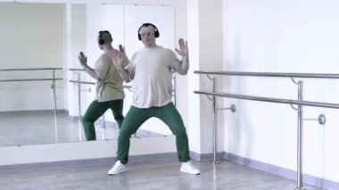 Bir break dansçı müzik kulaklıklarıyla dans eder. Erkeklerin elleri ağır çekimde plastik dans hareketleri. Koreografi salonunda dans provası..