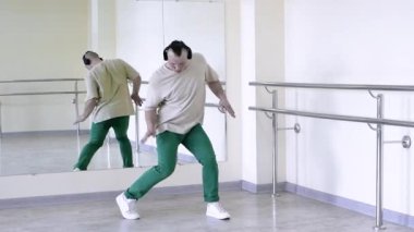 Break dansçı dans provası yapıyor. Spor salonundaki aynanın arka planına karşı modern dans. Genç bir adamın ritmik dansı..