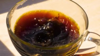 Şeffaf bir fincanda demlenmiş afromatik kahve, yavaş çekimde fincana bir damla kahve düşer. Yakın plan..