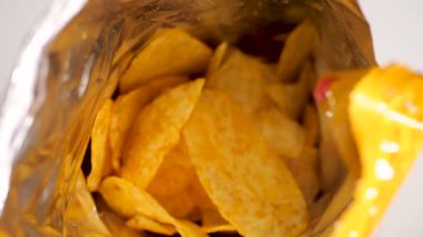 Bir adam folyo paketinden patates cipsi yiyor, yakın plan. Bir adam gümüş bir paketten fiş çıkarır.