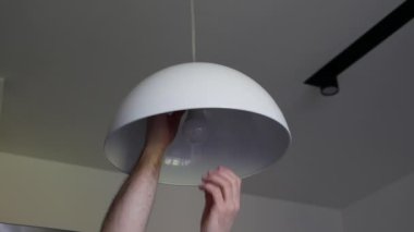 Bir adam yanmış bir ampulü söker. Işıklıyı lambayla değiştirmek. Çatı katı ışığı.