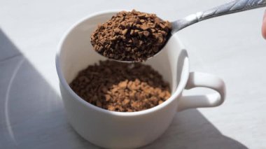 Yavaş çekimde hazır kahveyi kahve bardağına dök. Manzara, hazır kahve çekirdekleri ve kaşık..