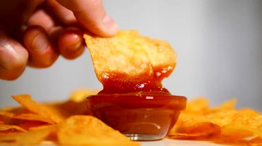 Patates cipsini yavaş çekimde kırmızı sosa batırmak. Tatlı soslu lezzetli cipsler ye. Fast food konsepti.