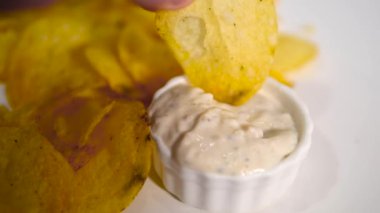 Mayonez sosuna batırılmış patates cipsi ye. Yavaş çekimde bir parça cipsi beyaz sarımsak sosuna batırıyorum.