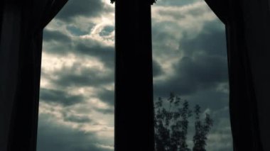 Dramatik kara bulutlar, bir evin penceresinden siyah bulutların zaman akışı. Pencerenin arka planında hareket eden bulutlar var.