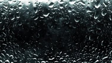 Yağmur damlalarıyla soyut bir arkaplan. Penceredeki su dokusu. Güzel damlalar yakın planda akıyor.