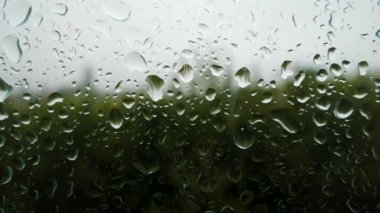 Camdaki güzel damlaların dokusu, pencerenin dışındaki yağmur. Cam bir pencerenin arkasındaki yaz fırtınası, bulanık Bokeh 'in arka planına karşı