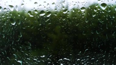 Pencerenin dışında yağmur yağıyor, rüzgar ağaçları şiddetle sallıyor, iklim değişiyor. Damlalar pencere camından aşağı akıyor.